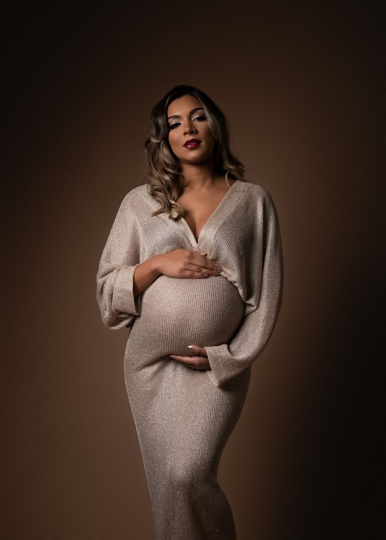 Maternity portrait in a gold knit dress on brown