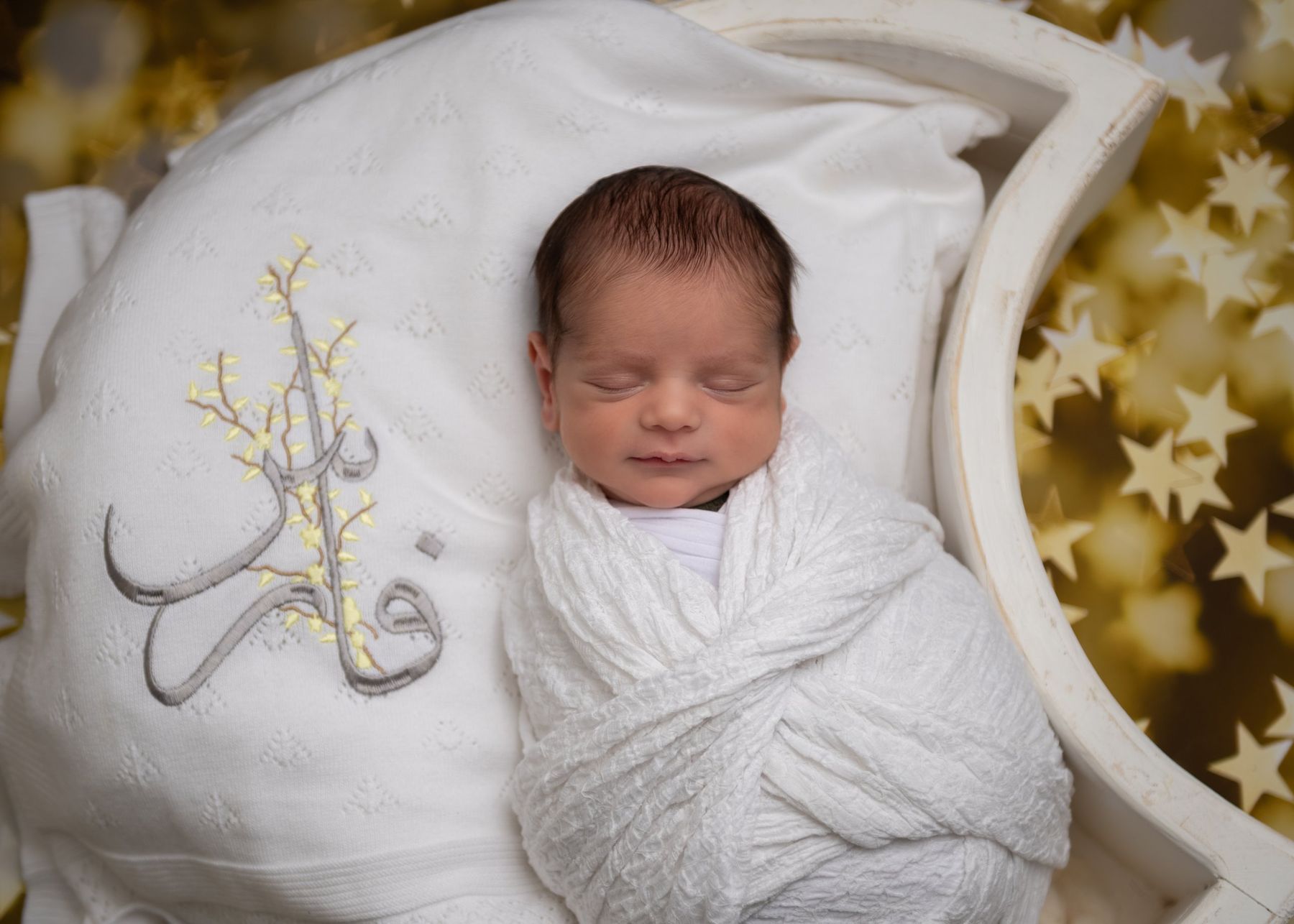Newborn with a blanket embroidered with his name in Arabic