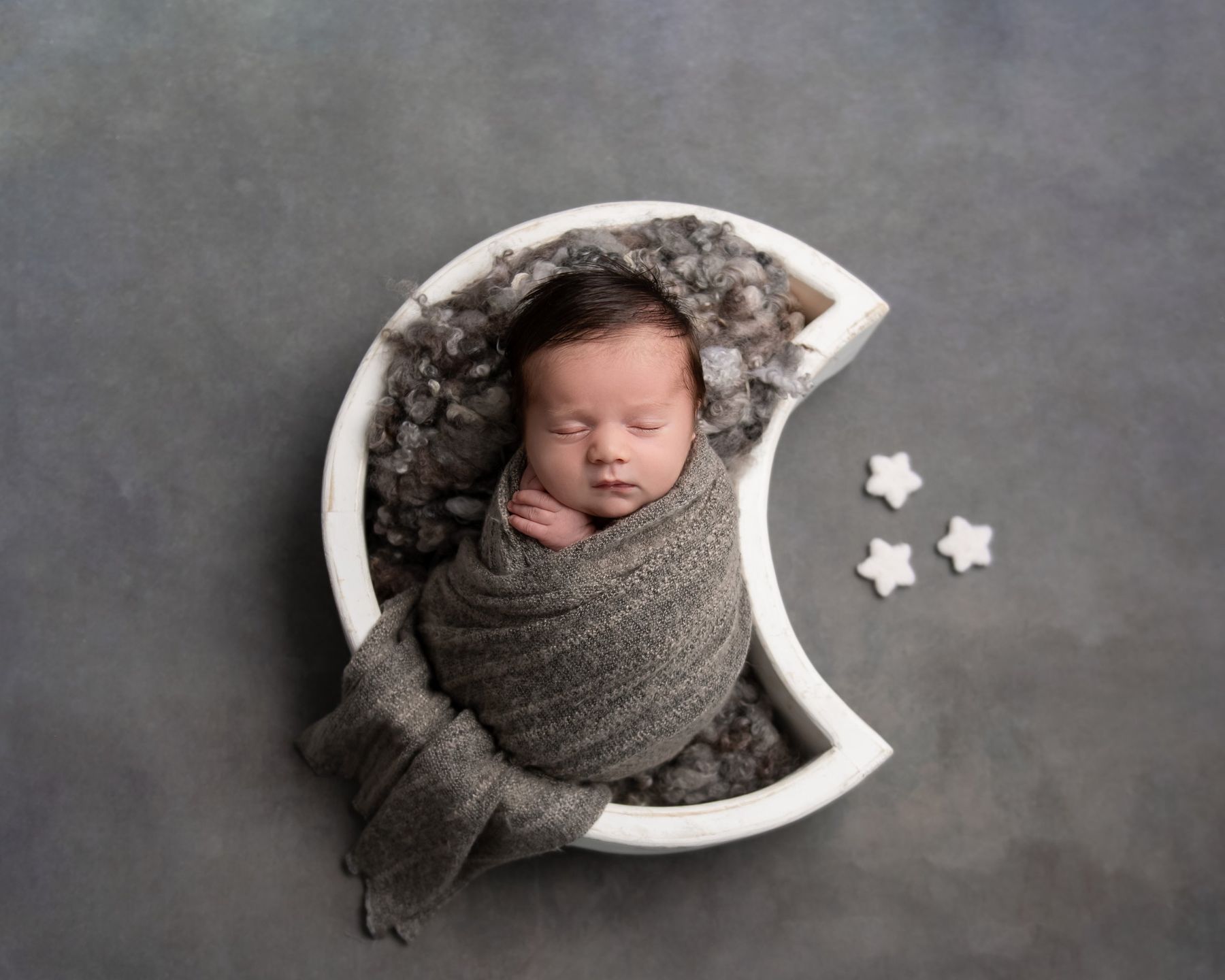 תינוק בקערת ירח לבנה על רקע אפור