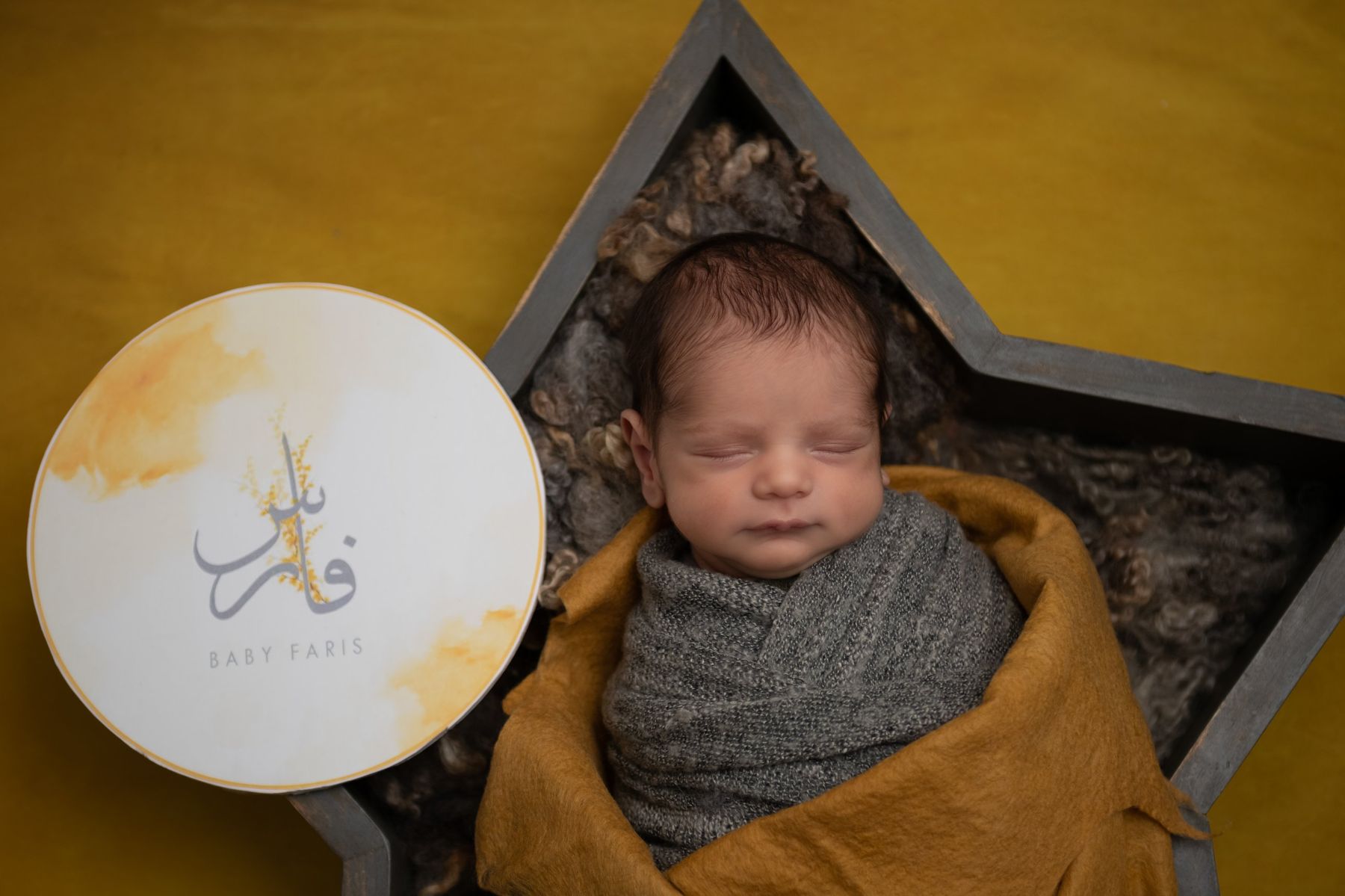Newborn in a star bowl with an Arabic name sign