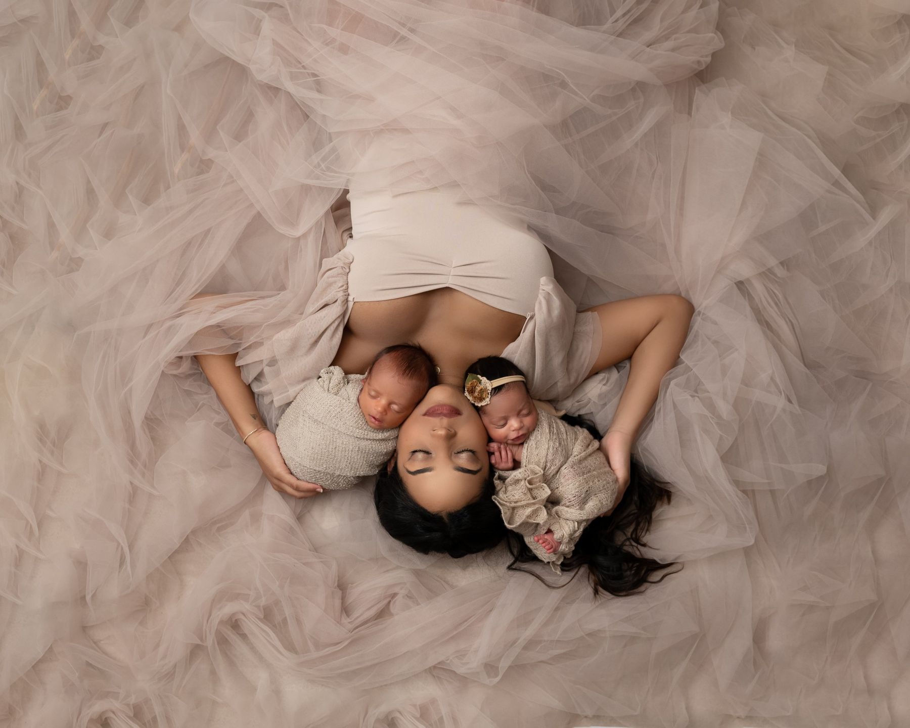 Mother with newborn twins on tulle, from above