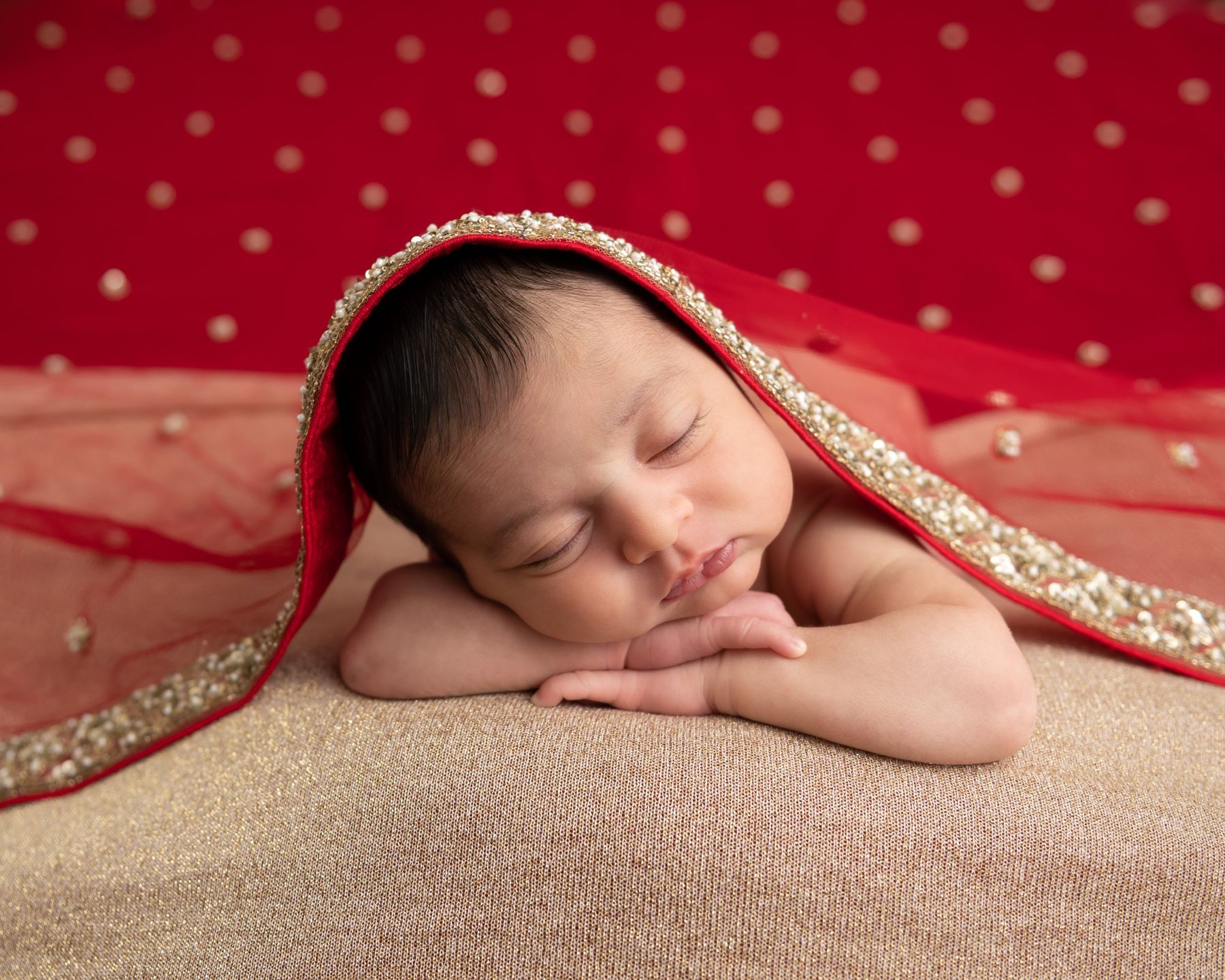 Newborn under a red embroidered veil