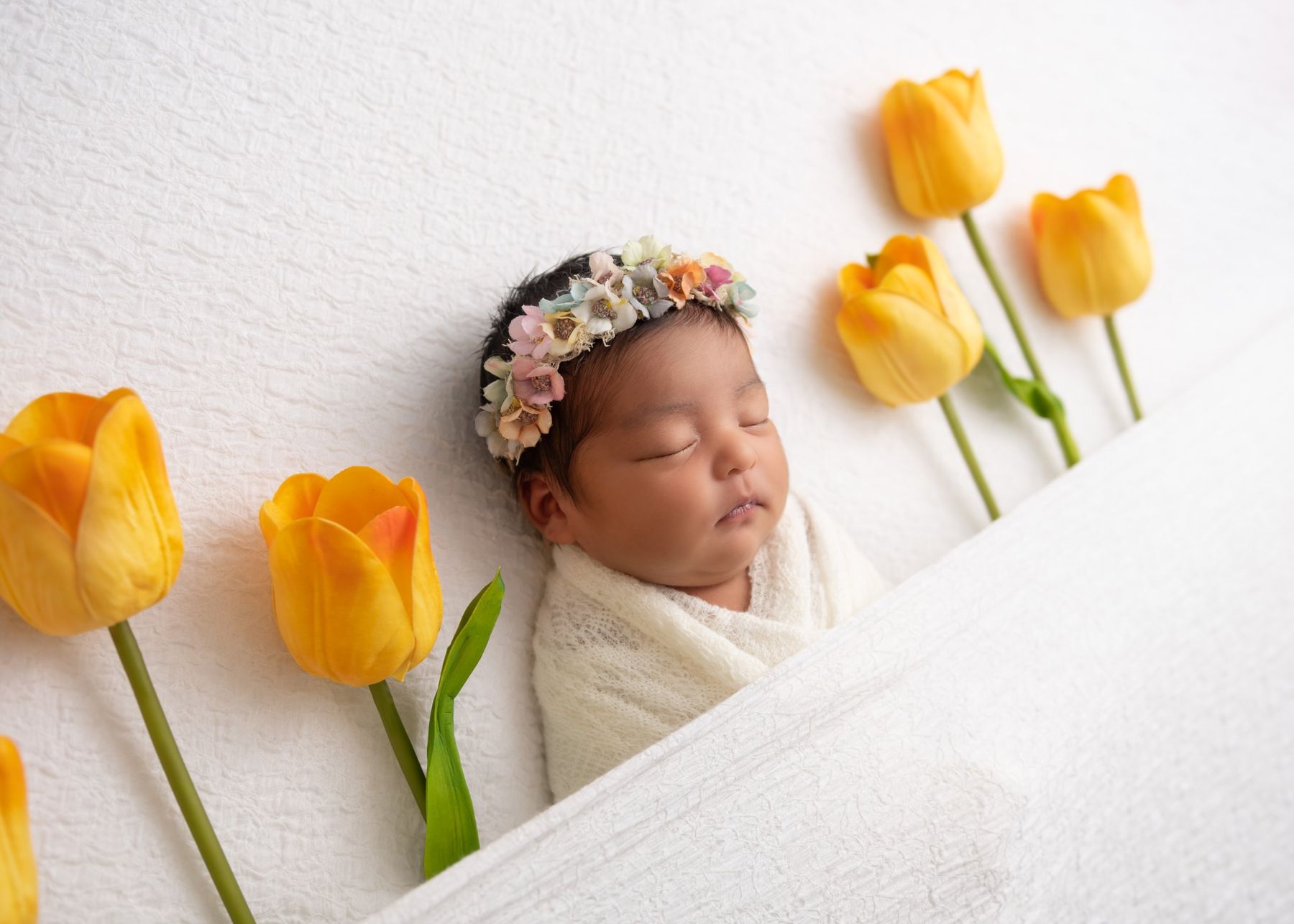 Newborn with a flower crown and yellow tulips